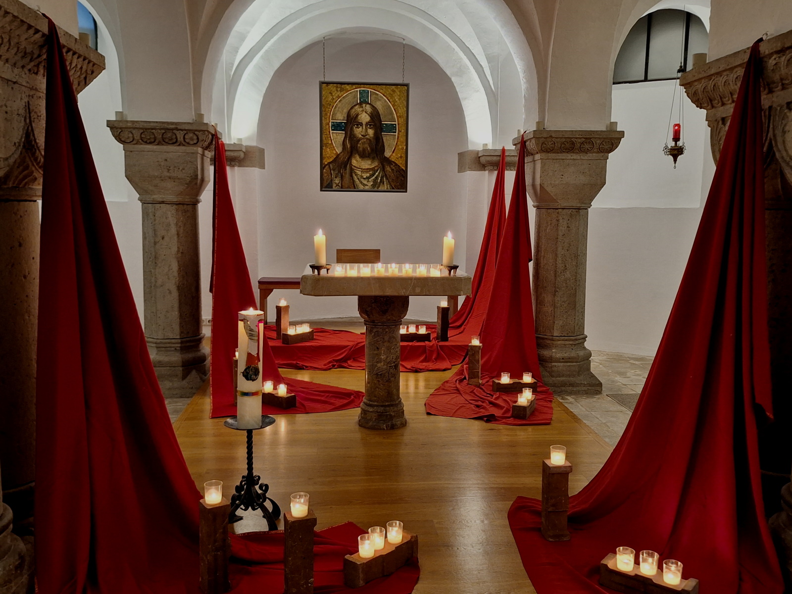Mit Kerzen und Tüchern gestalteter Altarraum der Krypta der St.-Benno-Kirche bei einem Taizégebet.